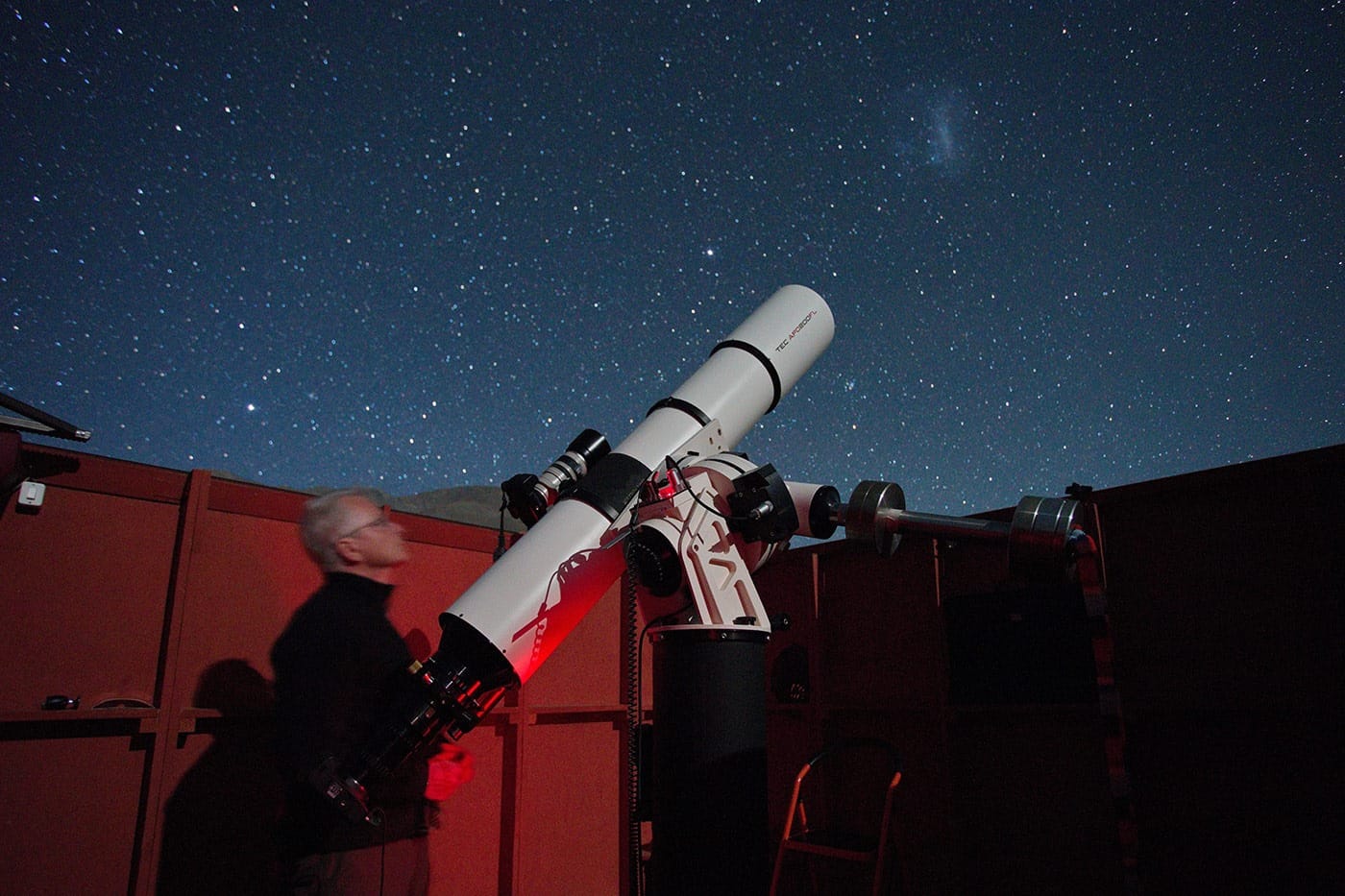 Ein Astrofotograf mit Linsenteleskop. Über ihm der Südsternhimmel mit der Großen Magellanschen Wolke, Rechte: Uwe Reichert