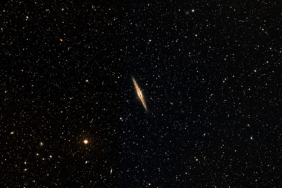 Wie eine dünne Spindel erscheint die Spiragalaxie NGC891, deren Scheibe wir direkt von der Kante sehen.