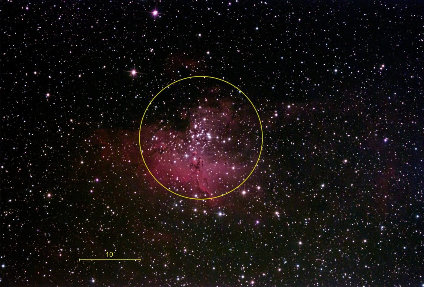 Der offene Sternhaufen M16 ist in einen rot leuchtenden Emissionsnebel eingebettet. Ein gelber Kreis markiert den ungefähren Rand des Sternhaufens.