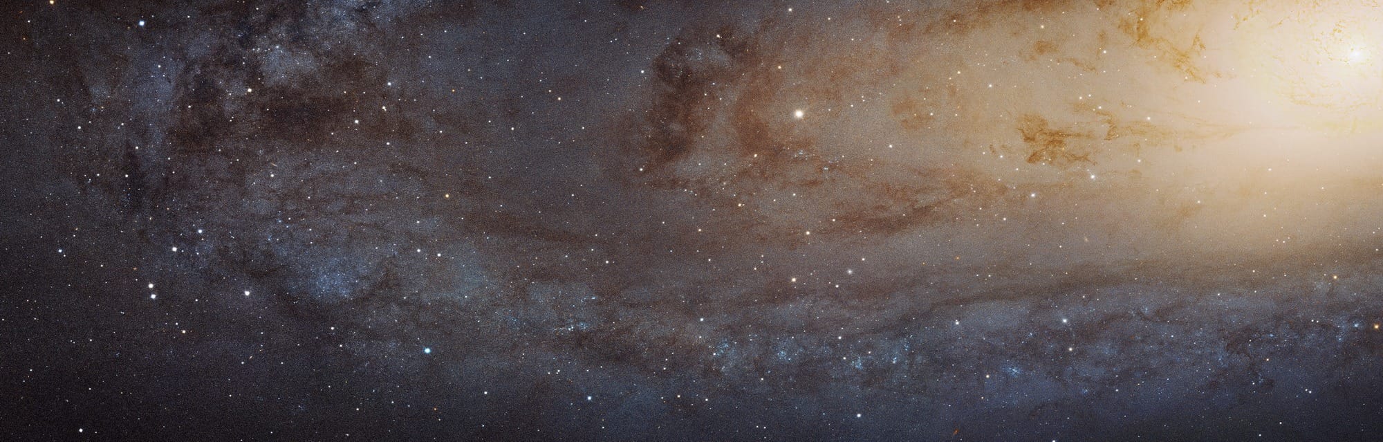 Dieser Ausschnitt der Andromedagalaxie reicht vom hellen Zentrum rechts oben bis in die nordöstlichen Außenbezirke, in denen bläulich leuchtende Sternentstehungsgebiete von dunklen Staubstreifen durchsetzt sind.