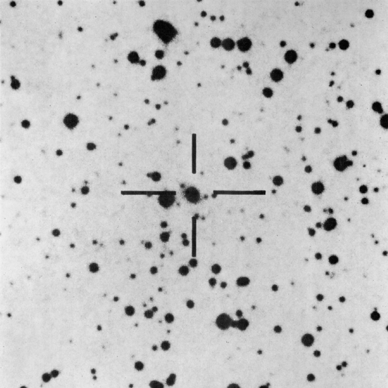 Eine Fotoplatte des Palomar-Observatoriums zeigt schwarze Sterne auf hellem Grund. Ein Fadenkreuz markiert das sternförmige Objekt BL Lacertae, das von einem schwachen, diffusen Nebel umgeben ist